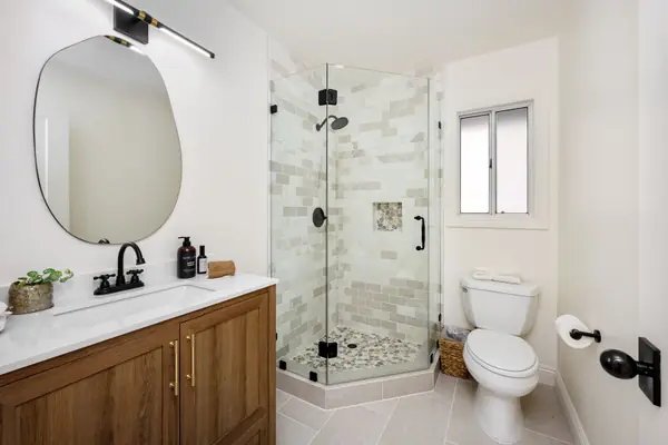 Baño reformado con ducha de cristal y acabados en madera